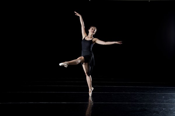 Asian ballerina dancing on dark stage