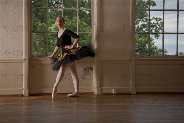 Caucasian ballerina posing at window in studio