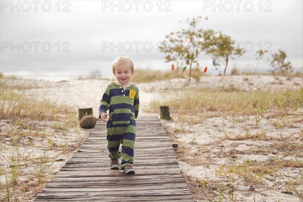 Caucasian boy walking on boardwalk at beach