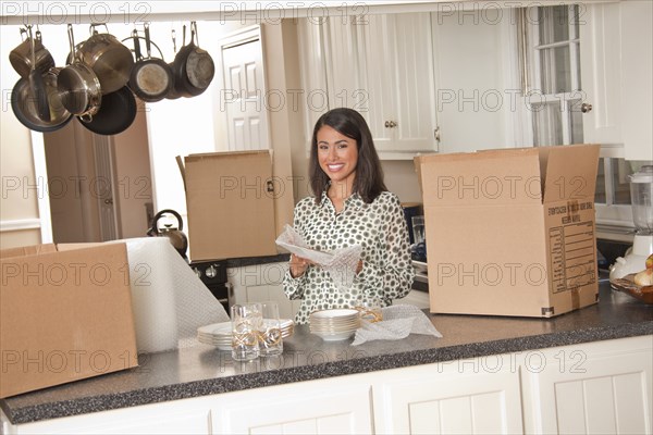 Smiling Hispanic woman packing dishes in kitchen