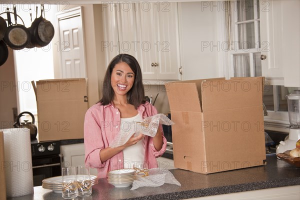 Smiling Hispanic woman packing dishes in kitchen