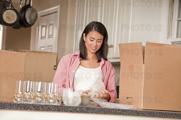 Smiling Hispanic woman packing dishes in kitchen