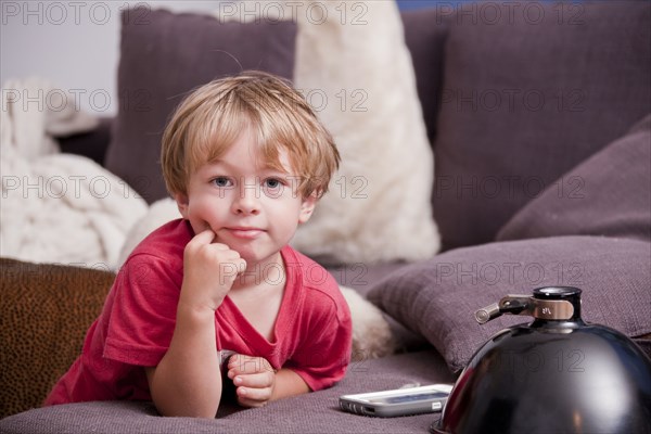 Caucasian boy leaning on sofa near cell phone