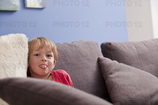 Caucasian boy with tongue out on sofa