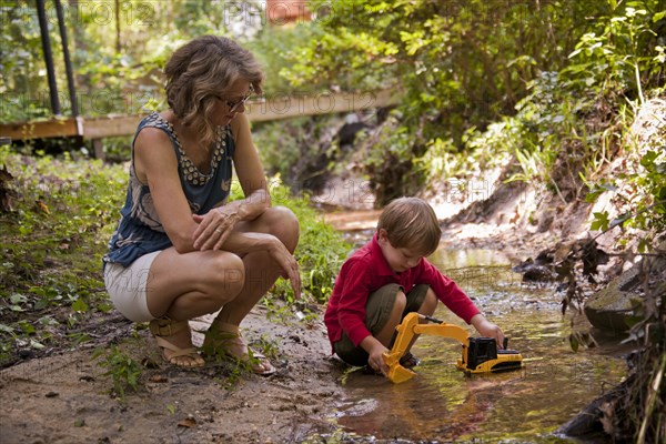 Caucasian mother watching son playing with construction toys in river