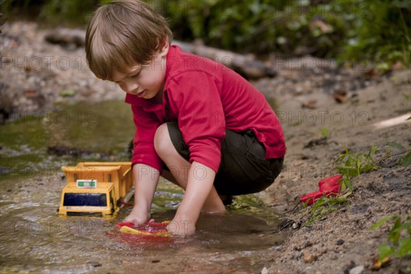 Caucasian boy playing with construction toys in river