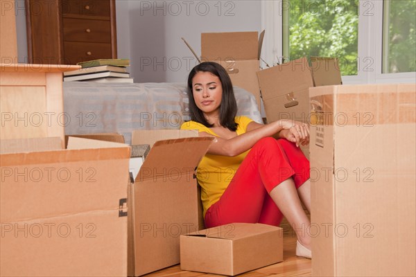 Hispanic woman sitting on floor with moving boxes