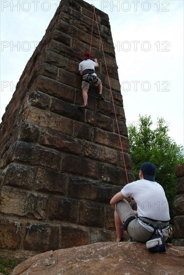 Spotter watching friend climbing urban brick wall