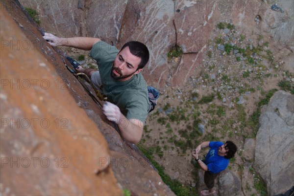 Spotter watching friend climbing urban brick wall