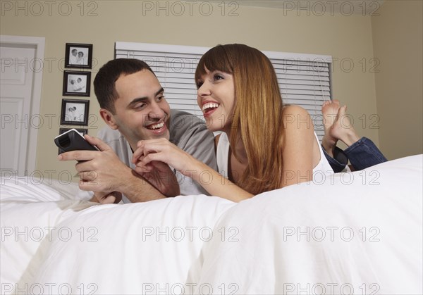 Hispanic husband and wife watching television in bedroom