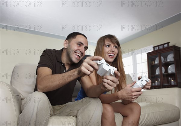 Hispanic husband and wife playing video game