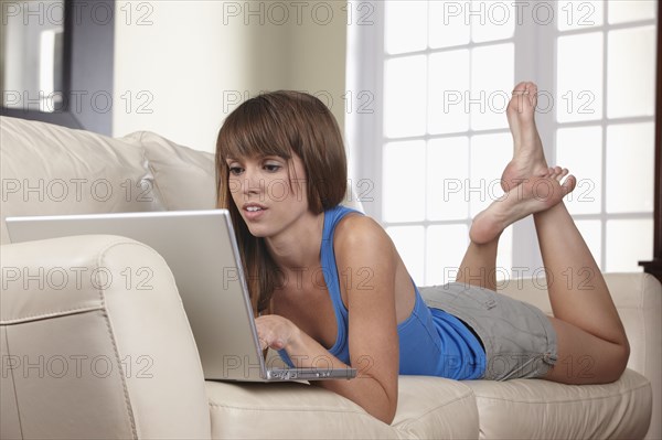 Mixed race woman using laptop on sofa