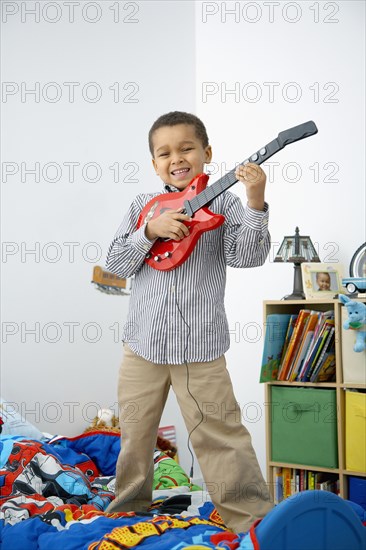 Mixed race boy playing toy guitar