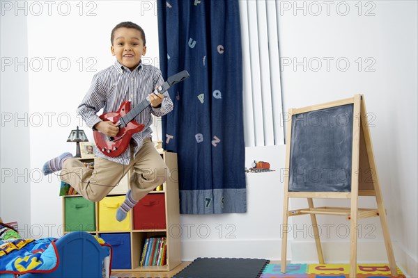 Mixed race boy playing toy guitar