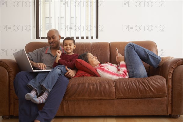 Antiguan man using laptop in living room with family