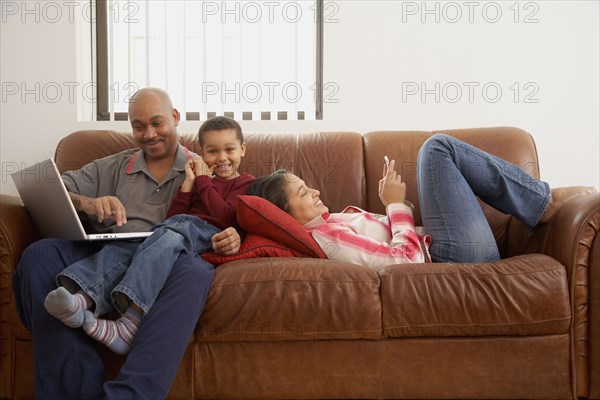 Antiguan man using laptop in living room with family