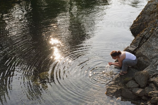 Hispanic woman washing face in lake