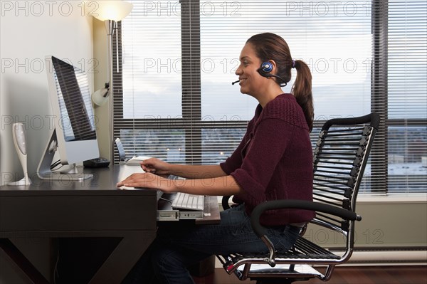 Hispanic woman in headset using computer