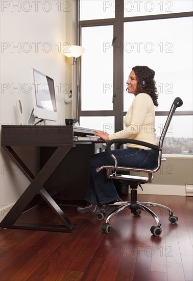 Hispanic woman in headset working on computer