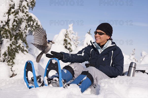 Bird perching on Hispanic woman's hand