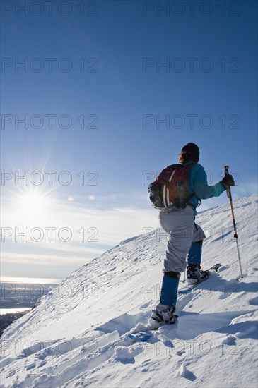Hispanic woman snowshoeing up hill
