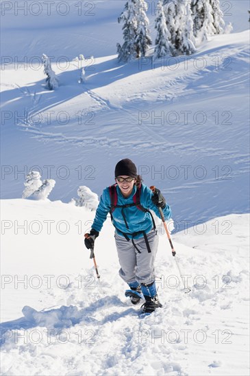 Hispanic woman snowshoeing up hill