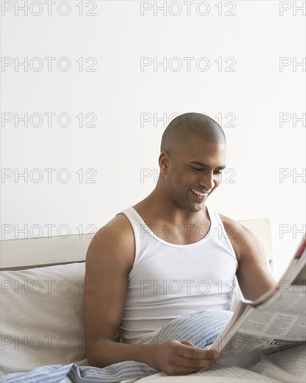 Man reading newspaper in bed