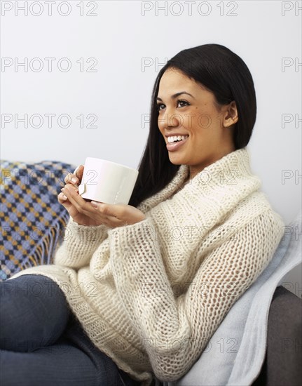 Woman sitting on sofa drinking coffee