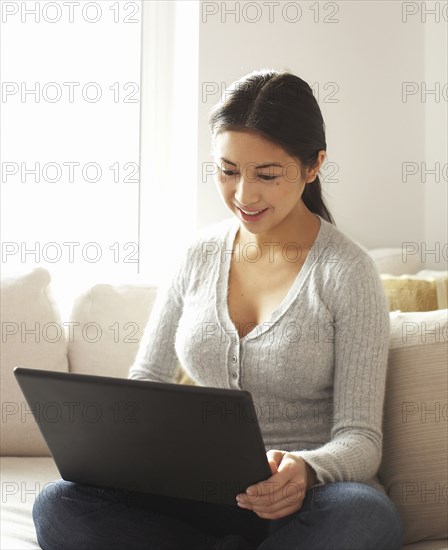 Woman sitting on sofa using laptop