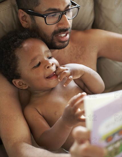 Father reading book to African American baby