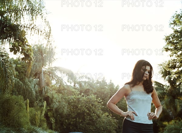 Woman standing outdoors with hands on hips