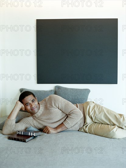 Man laying on bed with books