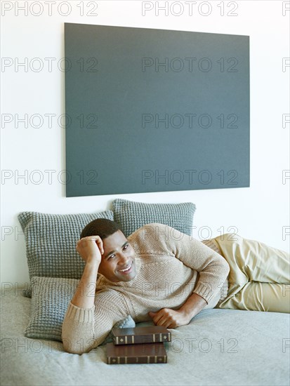 Man laying on bed with books