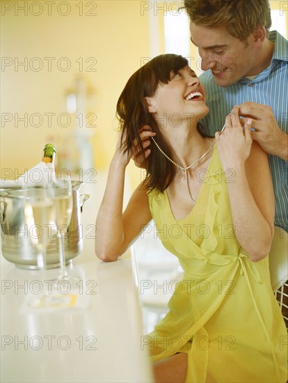 Man putting necklace on woman