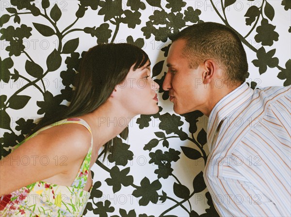 Couple face to face in front of wallpaper