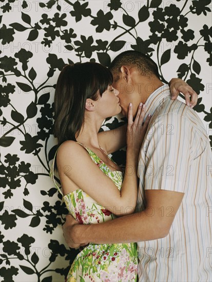 Couple kissing in front of wallpaper