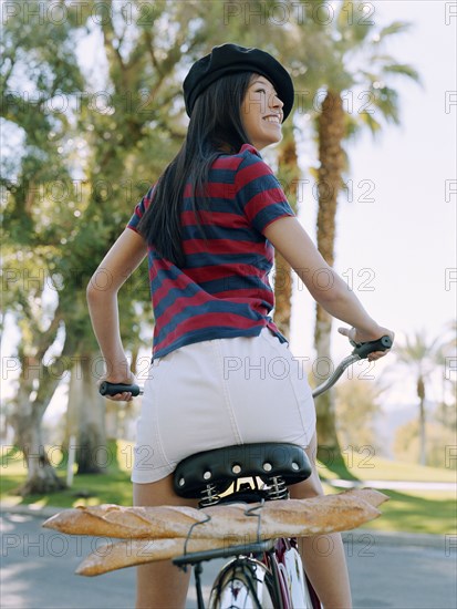 Woman riding bicycle with beret and baguettes