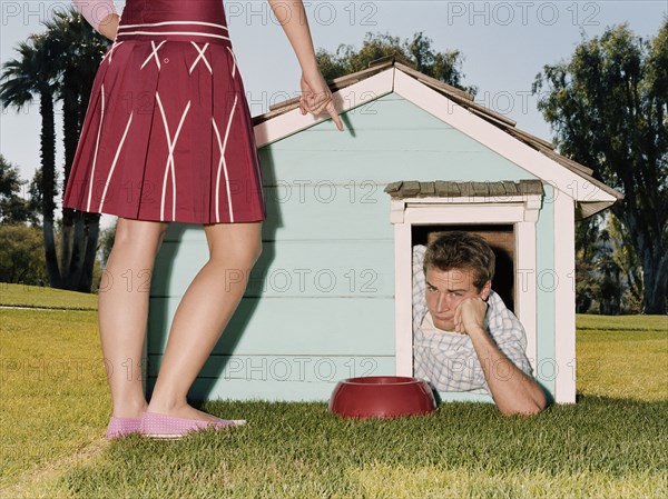 Frustrated man laying in doghouse