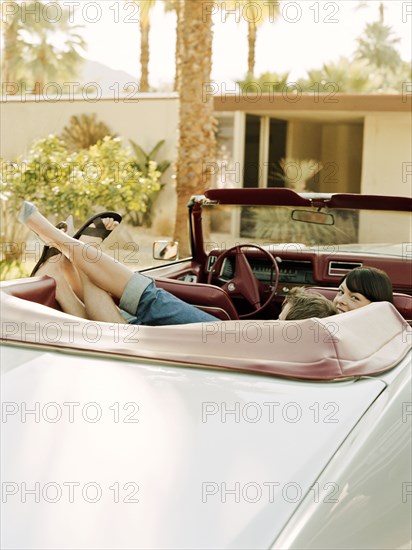 Couple laying in back seat of convertible