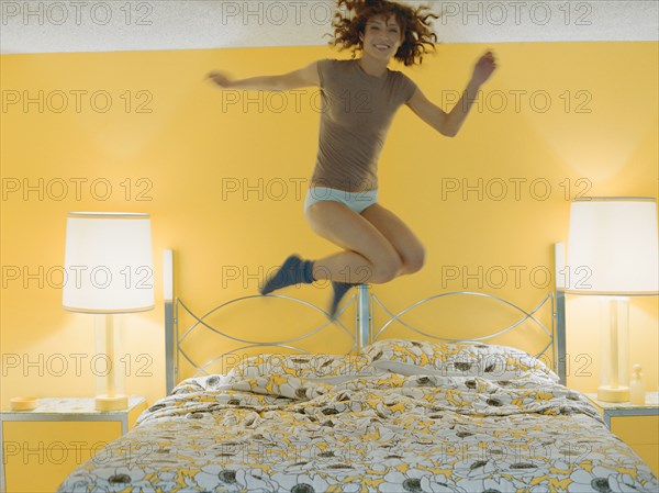 Woman jumping on bed