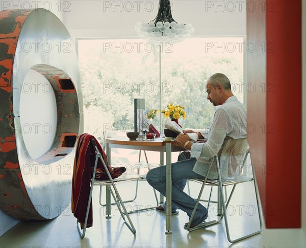 Caucasian man reading newspaper near metal sculpture