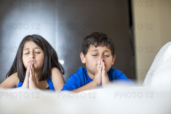 Close up of concerned Hispanic children praying