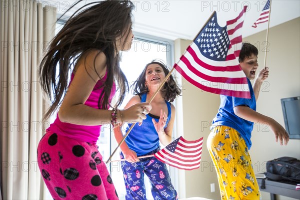 Hispanic children jumping with American flags