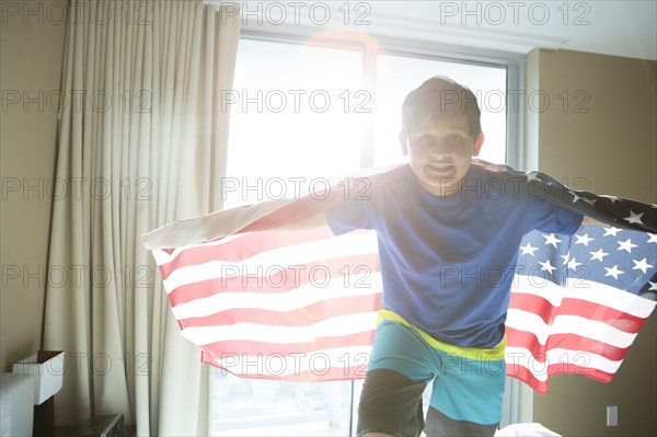 Hispanic boy using American flag as cape