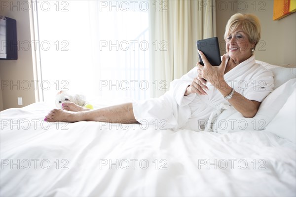 Older Caucasian woman using digital tablet on bed