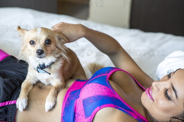 Hispanic athlete petting dog on bed