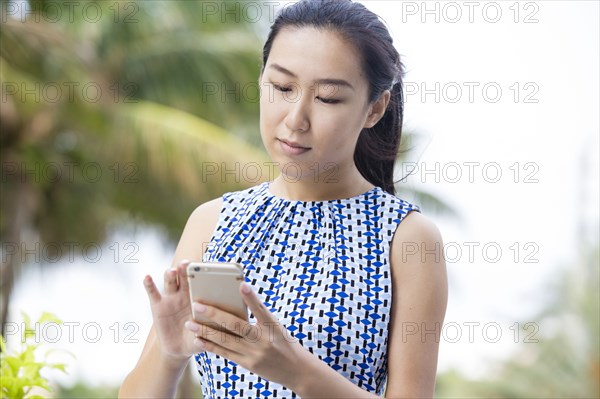 Asian businesswoman using cell phone outdoors