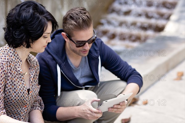 Caucasian business people using digital tablet by fountain