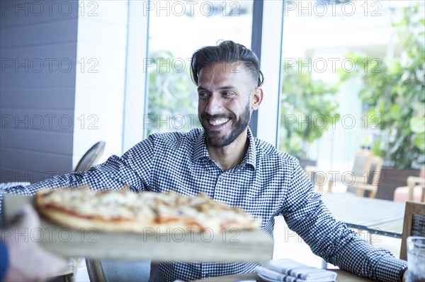 Server bringing diner pizza in restaurant