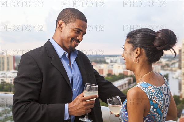 Couple drinking wine on urban balcony